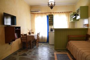 a bedroom with a bed and a table and a kitchen at Elia Studios Amorgos near the sea in Aegiali