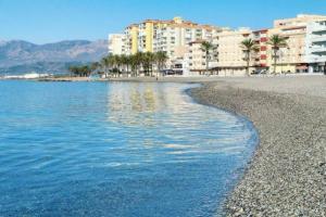 a beach with buildings and palm trees and the water at Precioso piso Torrenueva con Piscina y cerca Playa in Torrenueva