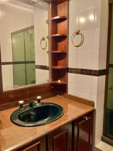 baño con lavabo verde y espejo en Apartamento Alto da Serra - 024, en Gramado