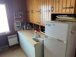 La cuisine est équipée d'un réfrigérateur blanc et de placards en bois. dans l'établissement Chalet situé au grand Valtin, à Ban-sur-Meurthe-Clefcy