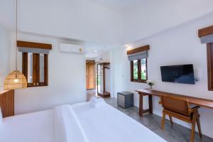 a bedroom with two beds and a desk and a tv at Phang Nga Origin Hotel in Phangnga