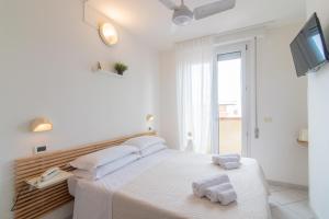 een witte slaapkamer met een bed met handdoeken erop bij HOTEL JOHN in Rimini