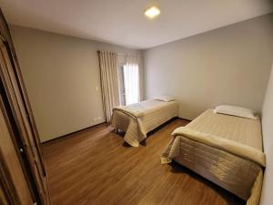 um quarto com duas camas e uma janela em Apartamento Vista Palace Centro em Poços de Caldas