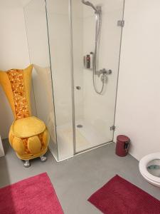a bathroom with a shower and a yellow chair at Loft Designer in Neuhausen am Rheinfall