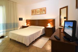 a bedroom with a bed and a desk with a television at Hotel Il Girasole in Villasimius