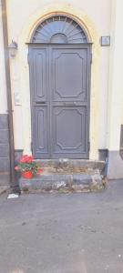 una gran puerta gris en un edificio con flores delante en OdeonHouse - Catania, en Catania