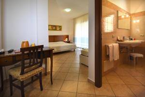 a hotel room with a bed and a desk and a bathroom at Hotel Il Girasole in Villasimius