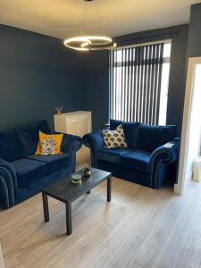 a living room with two blue couches and a coffee table at Luxury accommodation. in Wallasey