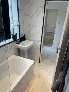 a white bathroom with a sink and a tub and a mirror at Luxury accommodation. in Wallasey