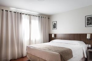 1 dormitorio con cama blanca y ventana en Hotel Dom Rafael Premium en Santa Maria
