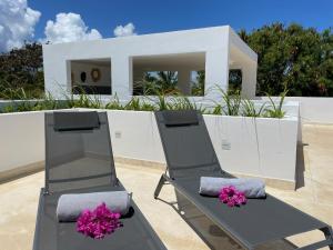 une paire de chaises sur une terrasse avec une maison dans l'établissement Tangawizi Villa with Private Pool ZanzibarHouses, à Kiwengwa