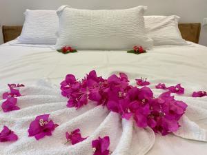 Una cama blanca con flores púrpuras. en Tangawizi Villa with Private Pool ZanzibarHouses en Kiwengwa