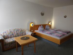Habitación con sofá, cama y mesa. en Hotel Garni, en Rodewisch