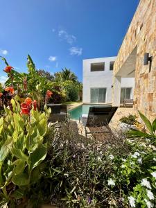 a house with a swimming pool and some flowers at Tangawizi Villa with Private Pool ZanzibarHouses in Kiwengwa