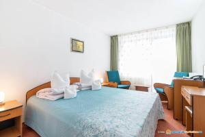 Hotel Bradul في دوراو: غرفة نوم بسرير ازرق مع كراسي ونافذة
