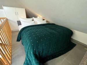 un letto con piumone verde in una camera di Haus-Berthin-Bleeg-App-6 a Wenningstedt