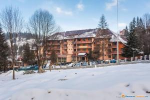 a large apartment building with snow on the ground at Hotel Bradul in Durau