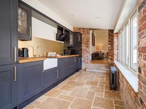 een keuken met blauwe kasten en een bakstenen muur bij Enchanted Cottage in Salhouse