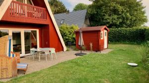un patio trasero con una casa roja, una mesa y una sombrilla en Ferienhaus Karlsson mit Blick auf die Ostsee en Hohenfelde