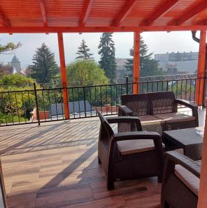 une terrasse en bois avec des chaises et des tables sur un balcon dans l'établissement Hotel Barbakán, à Pécs