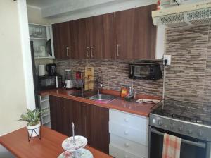 - une cuisine avec des placards en bois, un évier et une cuisinière dans l'établissement Departamento ubicado Playa Bellavista, Tomé, à Tomé