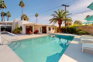 a swimming pool in front of a house with palm trees at Desert Willow Mod Permit# 5268 in Palm Springs
