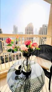 un vase avec des fleurs sur une table en verre sur un balcon dans l'établissement Lovely 1 Bedroom Luxury Apartment next to Burj Khalifa!! 24hr Concierge, Gym, Pool & Netflix - 29 Burj Boulevard in the heart of Downtown, à Dubaï