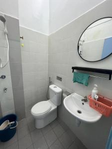 ein Badezimmer mit einem WC, einem Waschbecken und einem Spiegel in der Unterkunft Homestay Muslim D Permata Izhansif in Bandar Penawar