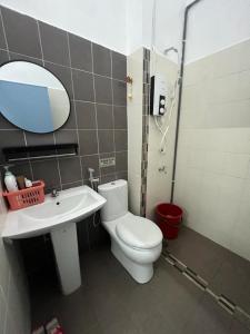 ein Badezimmer mit einem WC, einem Waschbecken und einem Spiegel in der Unterkunft Homestay Muslim D Permata Izhansif in Bandar Penawar