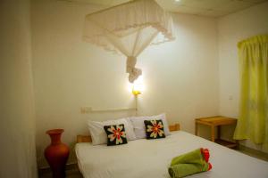 een slaapkamer met een wit bed met kussens erop bij Travelodge Sigiriya in Sigiriya