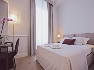 a bedroom with a white bed with a table and a window at Gemini Suites Navona in Rome