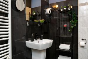 a bathroom with a white sink and black walls at Otium Old Town Boutique in Krakow +75 photos