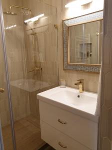a bathroom with a white sink and a shower at Apartman guru 1 in Szeged +18 photos