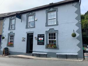 een wit gebouw met twee banken ervoor bij The Slaters Arms Corris in Machynlleth