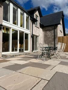 a patio with chairs and a bench in front of a house at Luxury Loch Tay Lodge in Aberfeldy