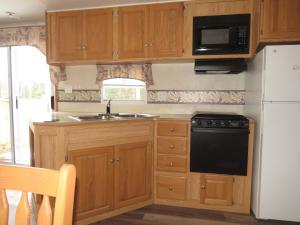 a kitchen with wooden cabinets and a sink and a microwave at Boardwalk RV Rental (Site #14) in Cavendish