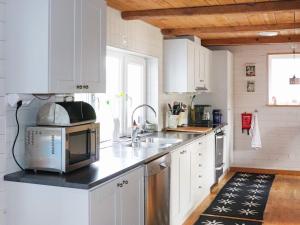 una cocina con armarios blancos y fregadero en Holiday home MUNKA-LJUNGBY VI, en Munka-Ljungby