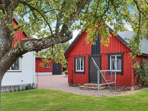 un granero rojo con un edificio blanco y un árbol en Holiday home MUNKA-LJUNGBY VI, en Munka-Ljungby