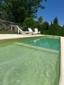 a swimming pool filled with green water with two chairs at Mi Sueño in San Antonio de Arredondo