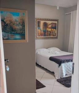 sypialnia z łóżkiem i 2 zdjęciami na ścianie w obiekcie Pousada Central w mieście São Benedito