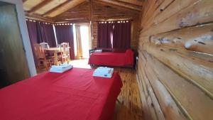 una habitación con una mesa roja en una cabaña de madera en Complejo majua en Cosquín