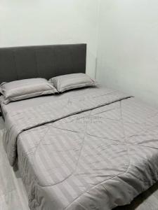 sypialnia z łóżkiem z białą pościelą i poduszkami w obiekcie Ali Homestay Sungai Petani w mieście Sungai Petani