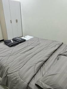 łóżko z szarą kołdrą w pokoju w obiekcie Ali Homestay Sungai Petani w mieście Sungai Petani