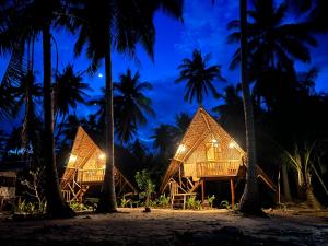 a resort on the beach at night with palm trees at Kanipa Beach Glamping in El Nido