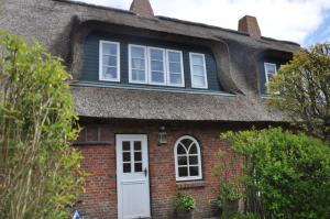 an old brick house with a thatched roof at Altes Standesamt Studiowohnung in Oldsum
