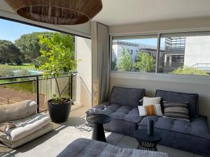 - un salon avec un canapé bleu et une grande fenêtre dans l'établissement Horizon Golf - Appart vue piscine et golf, à Saint-Cyprien