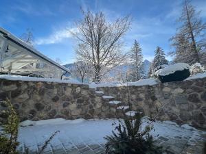 un muro di pietra ricoperto di neve accanto a una casa di Wholesome Holiday Base in nature a Gozd Martuljek