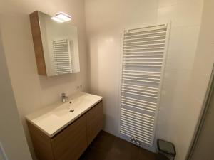 a white bathroom with a sink and a mirror at Triton suite Duinhof - Stijn Albrechtsstraat 1-6 in Cadzand +5 photos