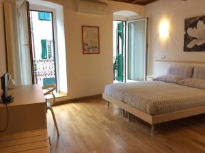 een slaapkamer met een bed, een bureau en ramen bij La Dolce Vita in Riomaggiore