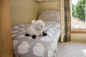 um urso de peluche sentado em cima de uma cama em the abberton shepherds hut em Evesham